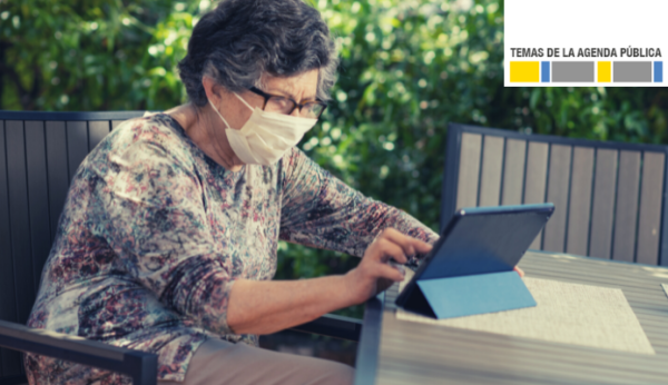 Mujer adulta mayor usando mascarilla viendo algo en un tablet